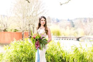 A bride holding a bouquet in front of tall grass.