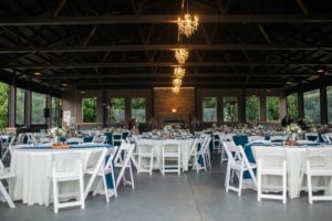 A wedding reception set up with white tables and chairs.