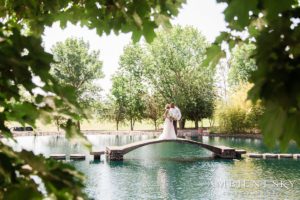 The newlyweds kissing on the bridge over the pond