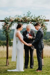 A bride and groom exchanging vows in a meadow.