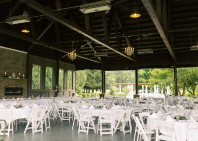 An outdoor wedding reception with white tables and chairs.