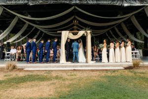 The bride and groom at the wedding arch with their attendants