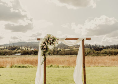 An archway with white cloth and flowers