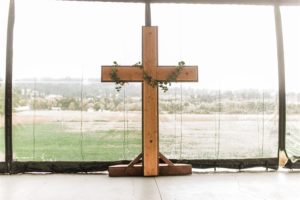 A wooden cross in front of a large window.