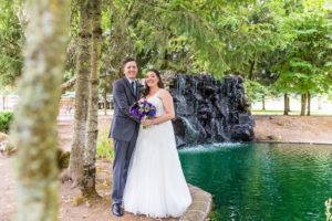 The newlyweds standing near the edge of the pond