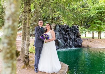 The newlyweds standing near the edge of the pond