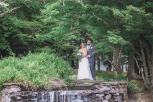 Shady grove design inspiration: A bride and groom embracing next to a waterfall in the woods.