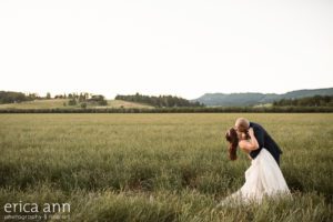 A bride and groom kissing in a field.