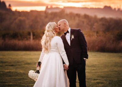 Newlyweds kissing at sunset on the lawn