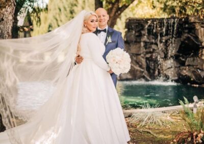 A bride and groom standing next to the pond and waterfall