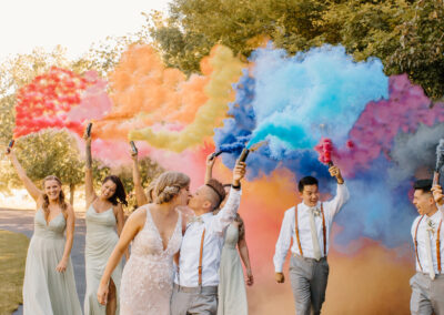 The newlyweds share a kiss with colorful smoke behind them