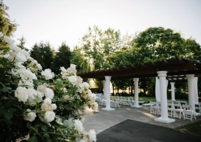 A wedding ceremony with white roses and a gazebo.